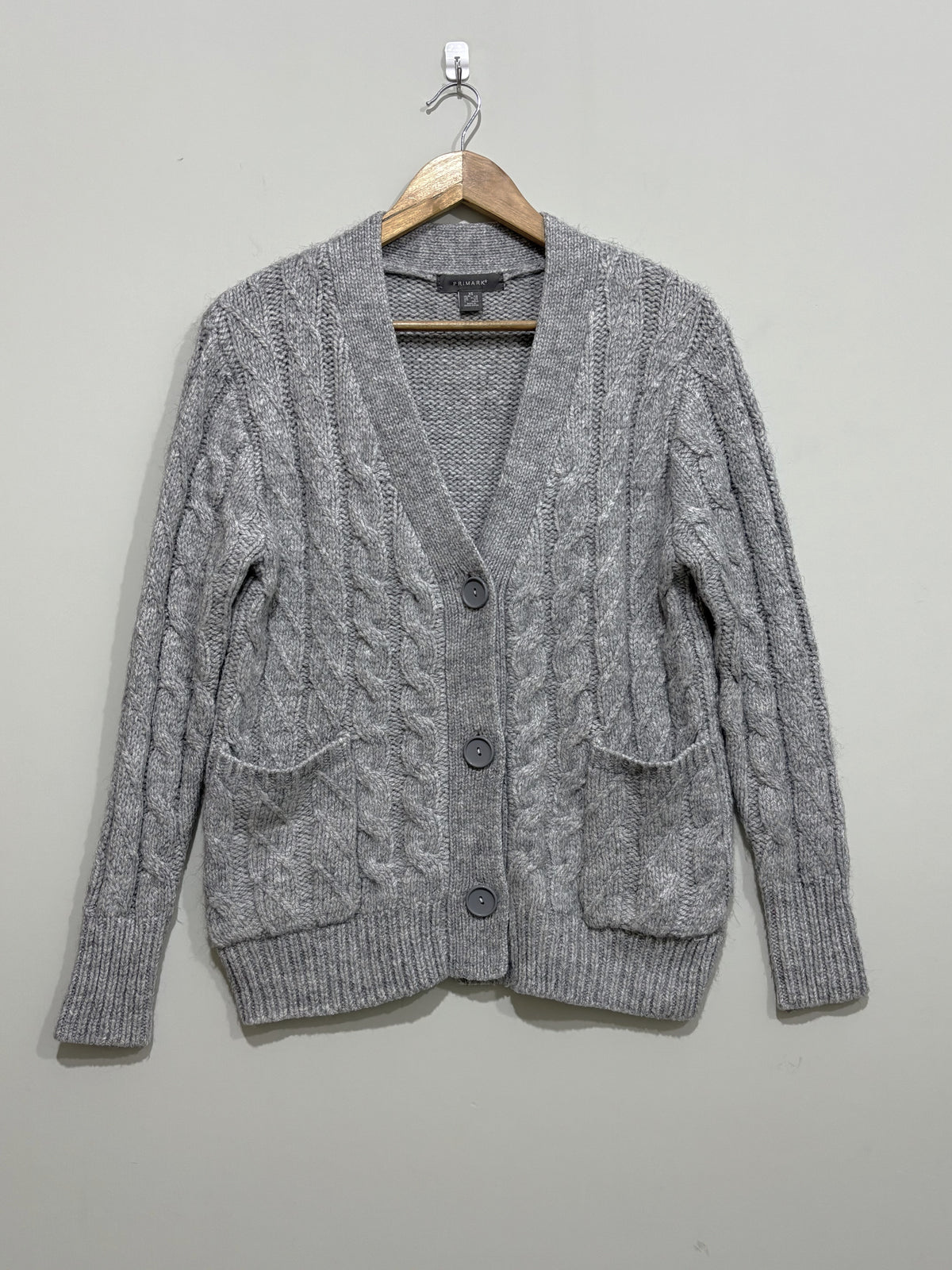 Grey cable-knit V-neck cardigan with three front buttons, two patch pockets, long sleeves and ribbed cuffs and hem.