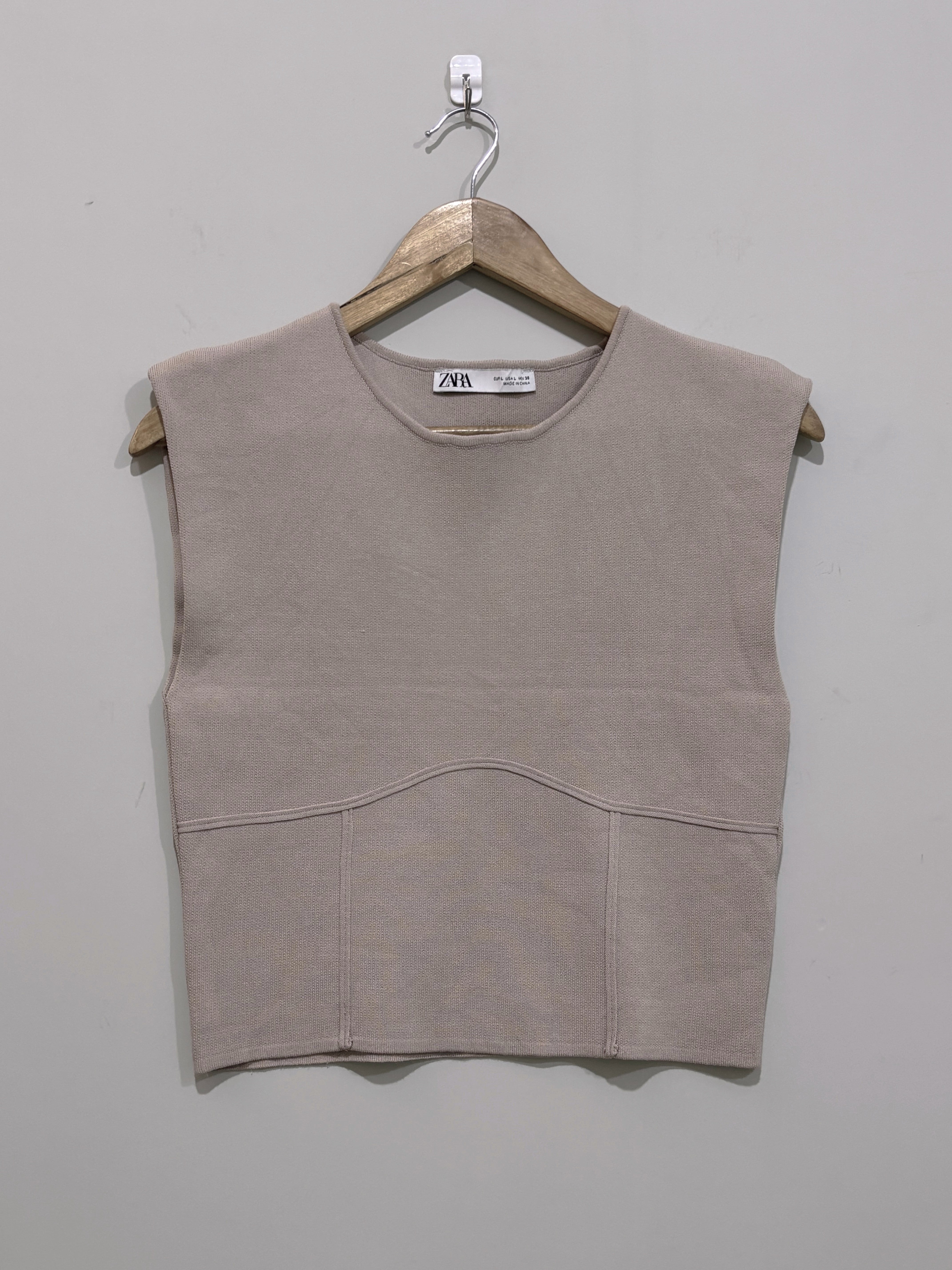 Taupe sleeveless round-neck crop top with wide shoulders, a curved front seam and panelled lower section.