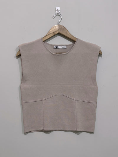 Taupe sleeveless round-neck crop top with wide shoulders, a curved front seam and panelled lower section.