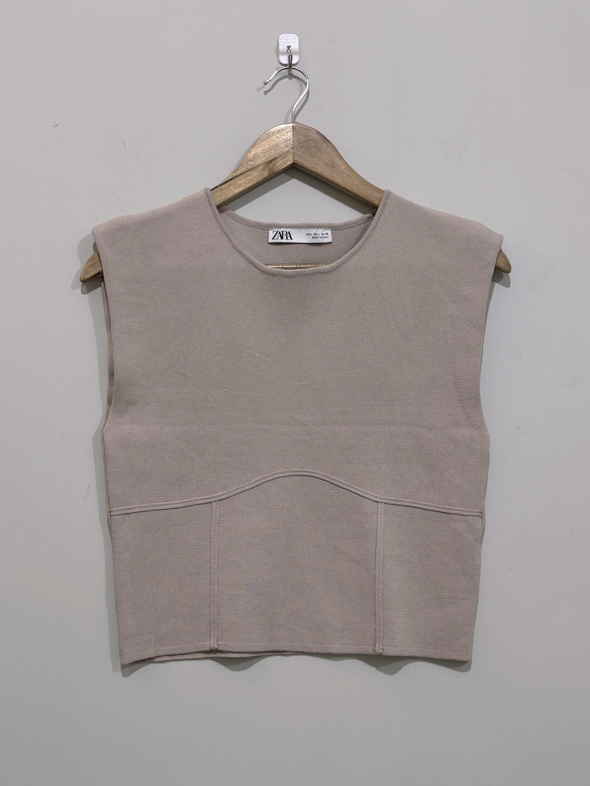 Taupe sleeveless round-neck crop top with wide shoulders, a curved front seam and panelled lower section.