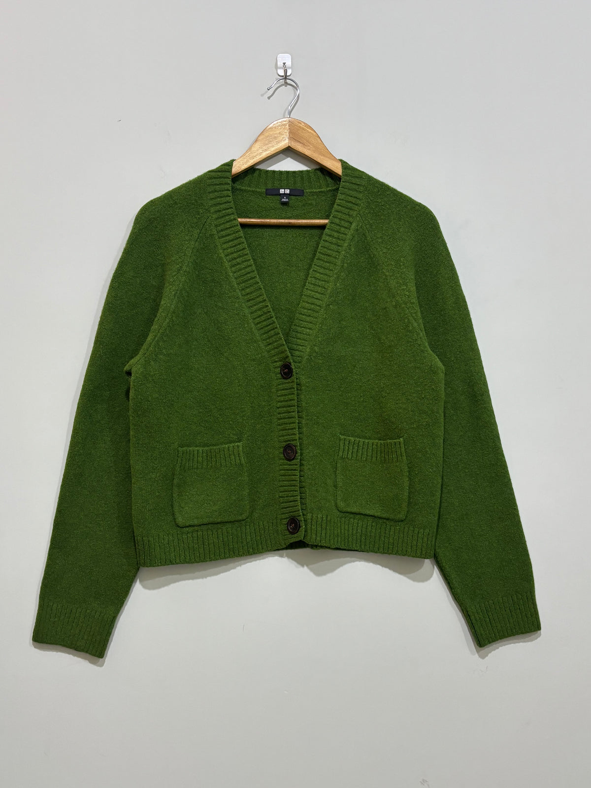 Olive green V-neck cardigan with three front buttons, two patch pockets, long sleeves and ribbed trims.