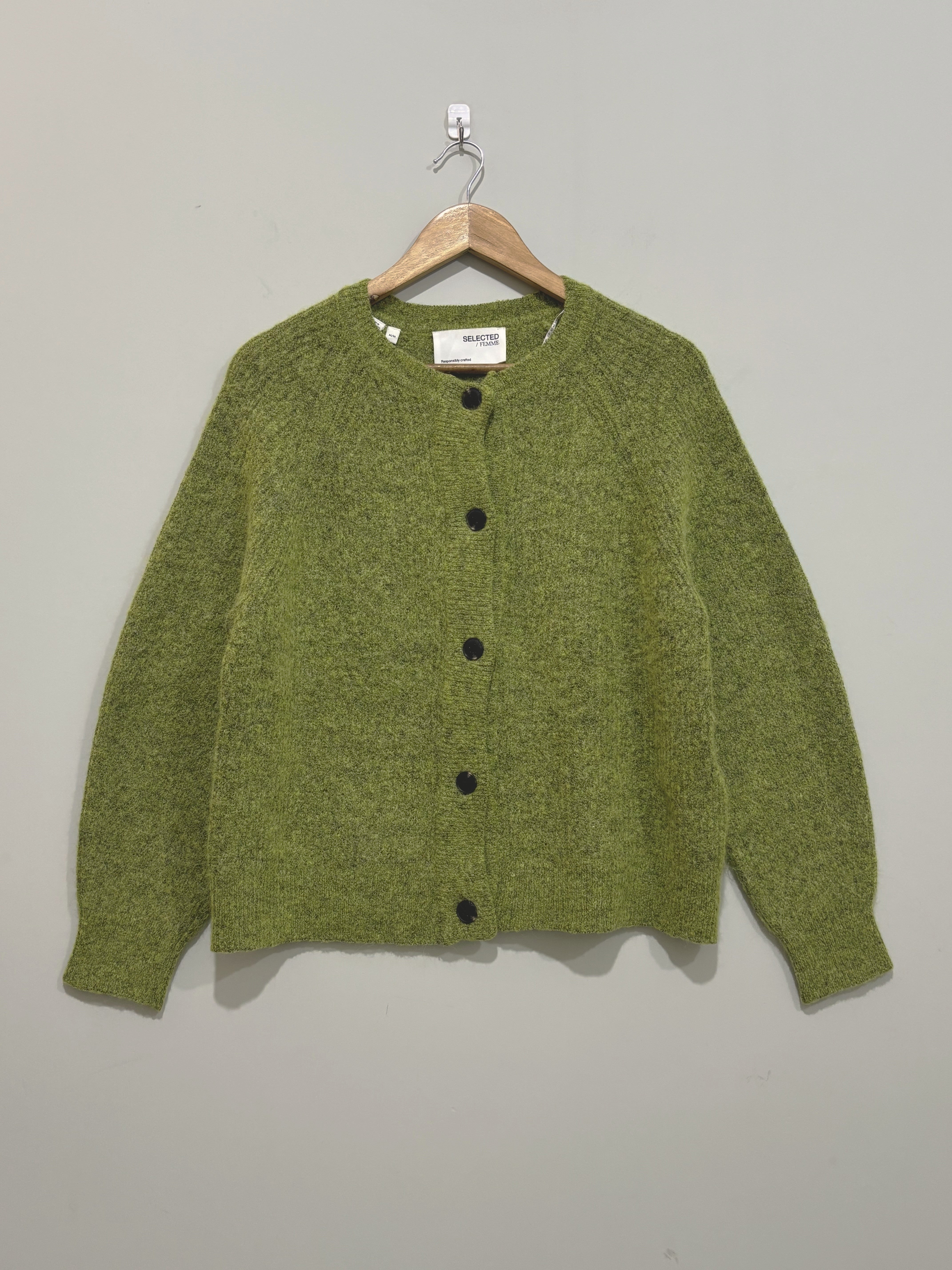 Olive green round-neck cardigan with five dark front buttons, long sleeves and ribbed trims on a wooden hanger.