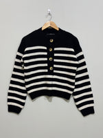 Black and cream horizontally striped sweater with drop shoulders, four front buttons, long sleeves and ribbed cuffs and hem.