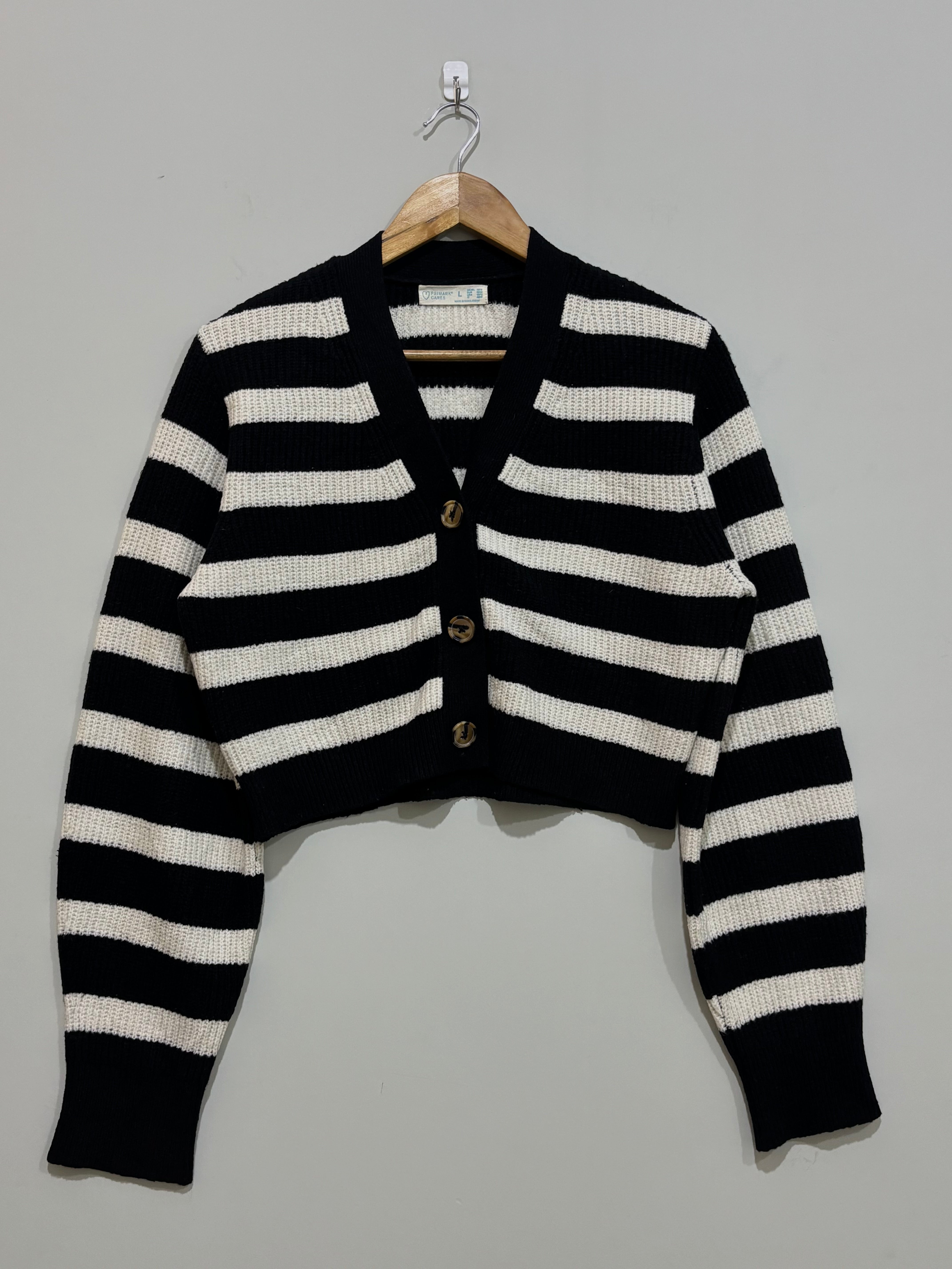 Black and white horizontally striped cropped cardigan with a V-neck, three front buttons, long sleeves and ribbed cuffs and hem.