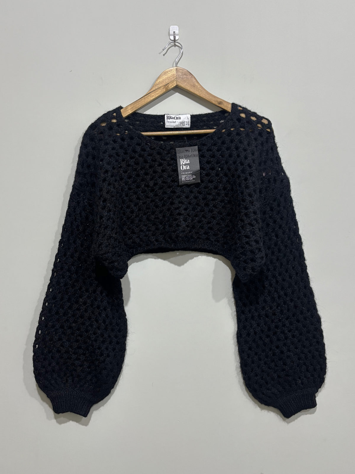 Black openwork cropped sweater with a round neckline, dropped shoulders and long balloon sleeves with fitted cuffs.