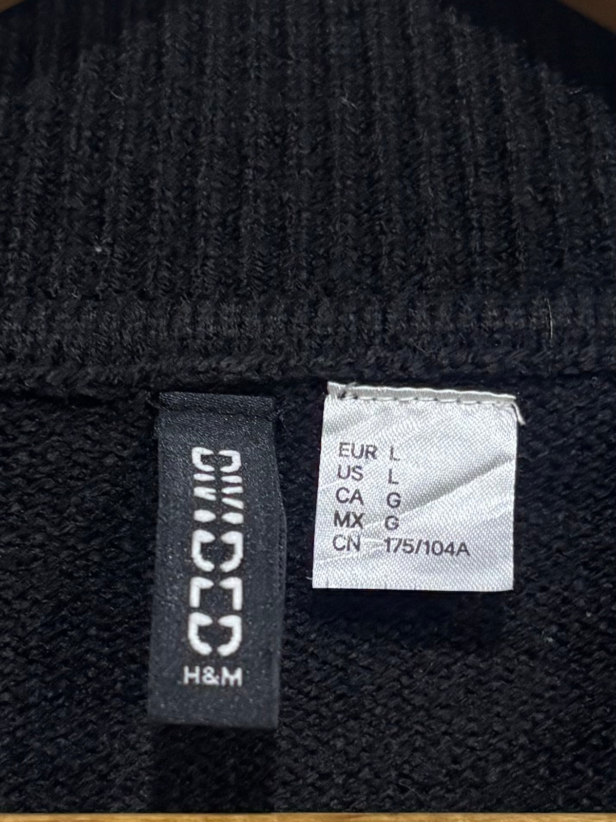 H&M Divided label showing EUR L and US L on the black knitted blouse.