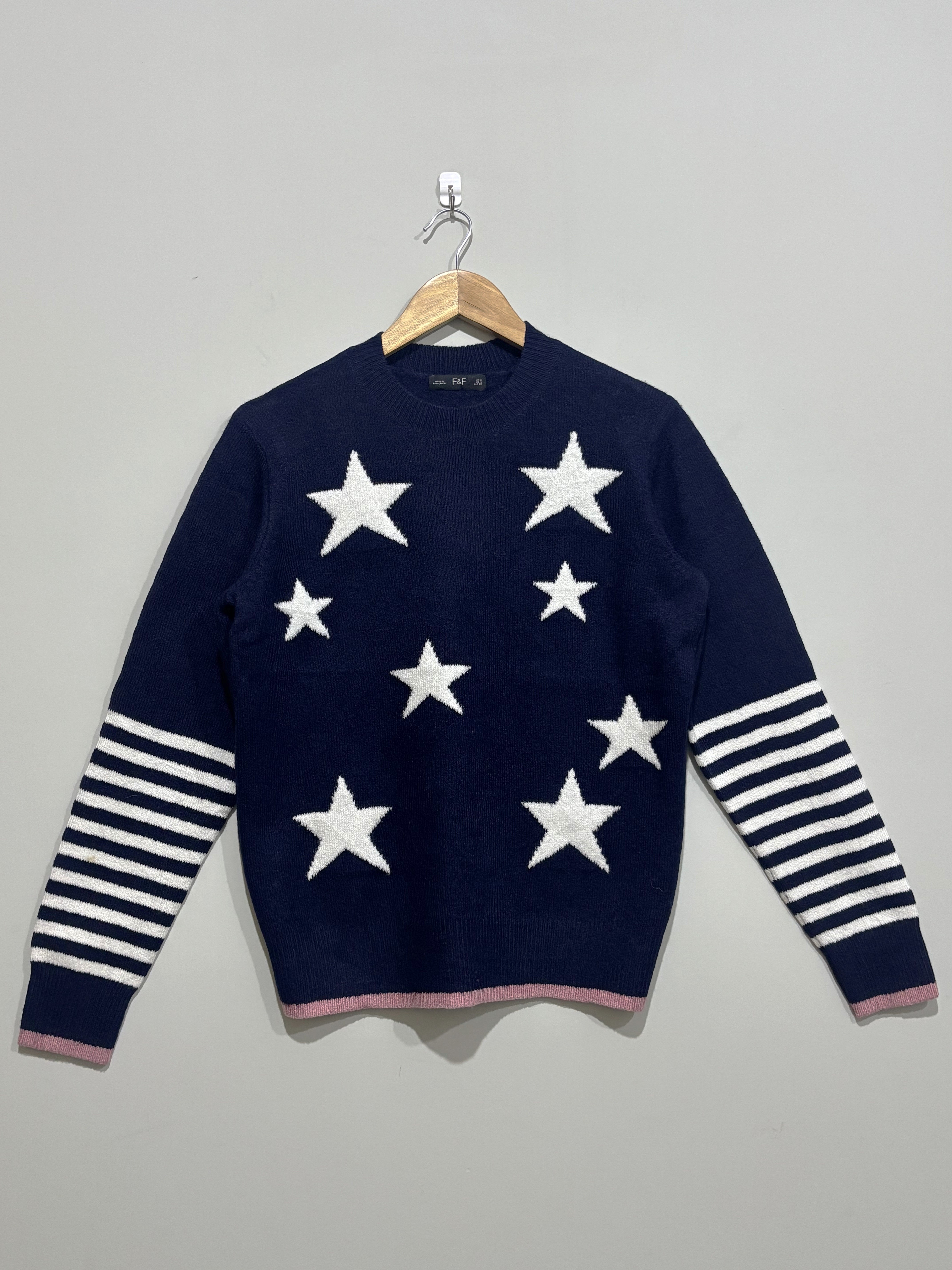 Navy blue crew-neck winter blouse with white stars, white striped sleeves and pink edging at the cuffs and hem.