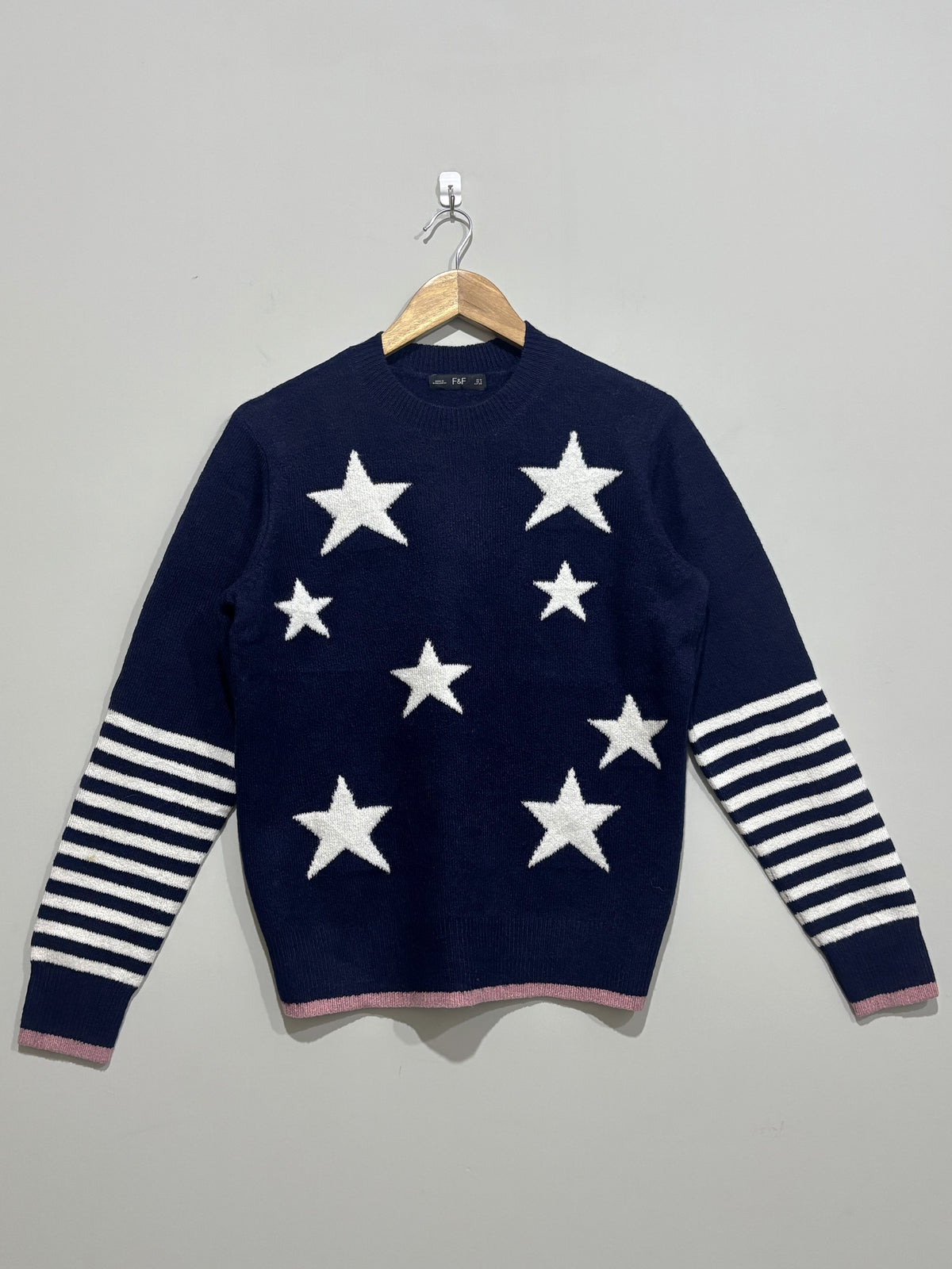 Navy blue crew-neck winter blouse with white stars, white striped sleeves and pink edging at the cuffs and hem.