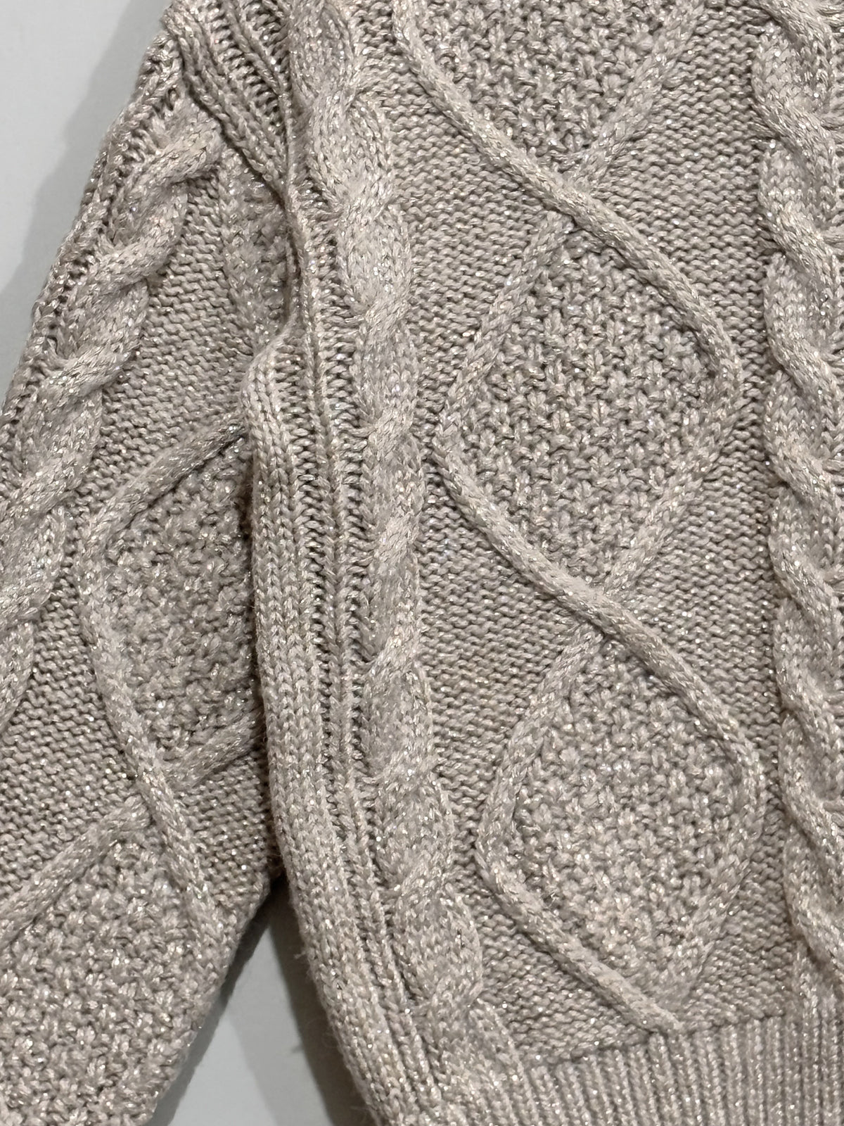 Close-up of beige diamond cable-knit panels and ribbed hem.