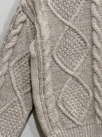 Close-up of beige diamond cable-knit panels and ribbed hem.