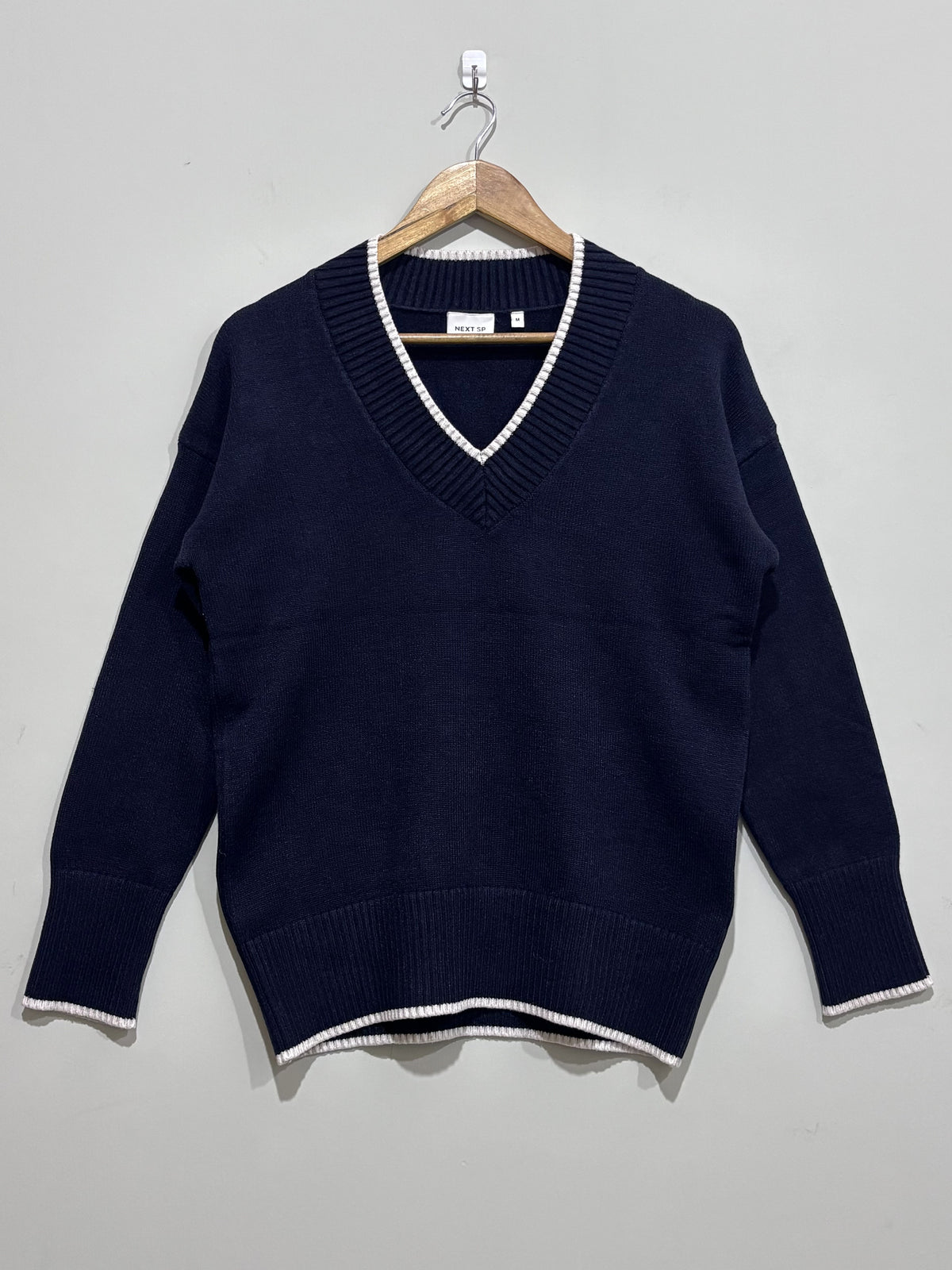 Navy blue V-neck pullover with light contrast edging along the neckline, cuffs and hem, long sleeves and deep ribbed trims.