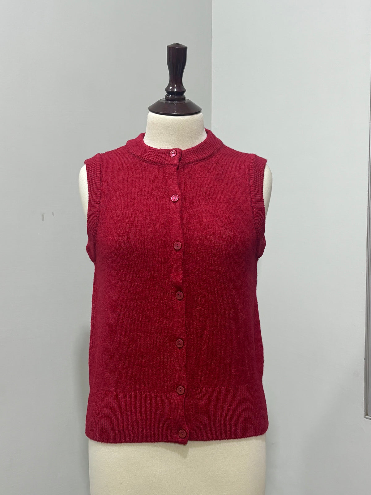 Red button-front knitted vest with ribbed edging on a mannequin