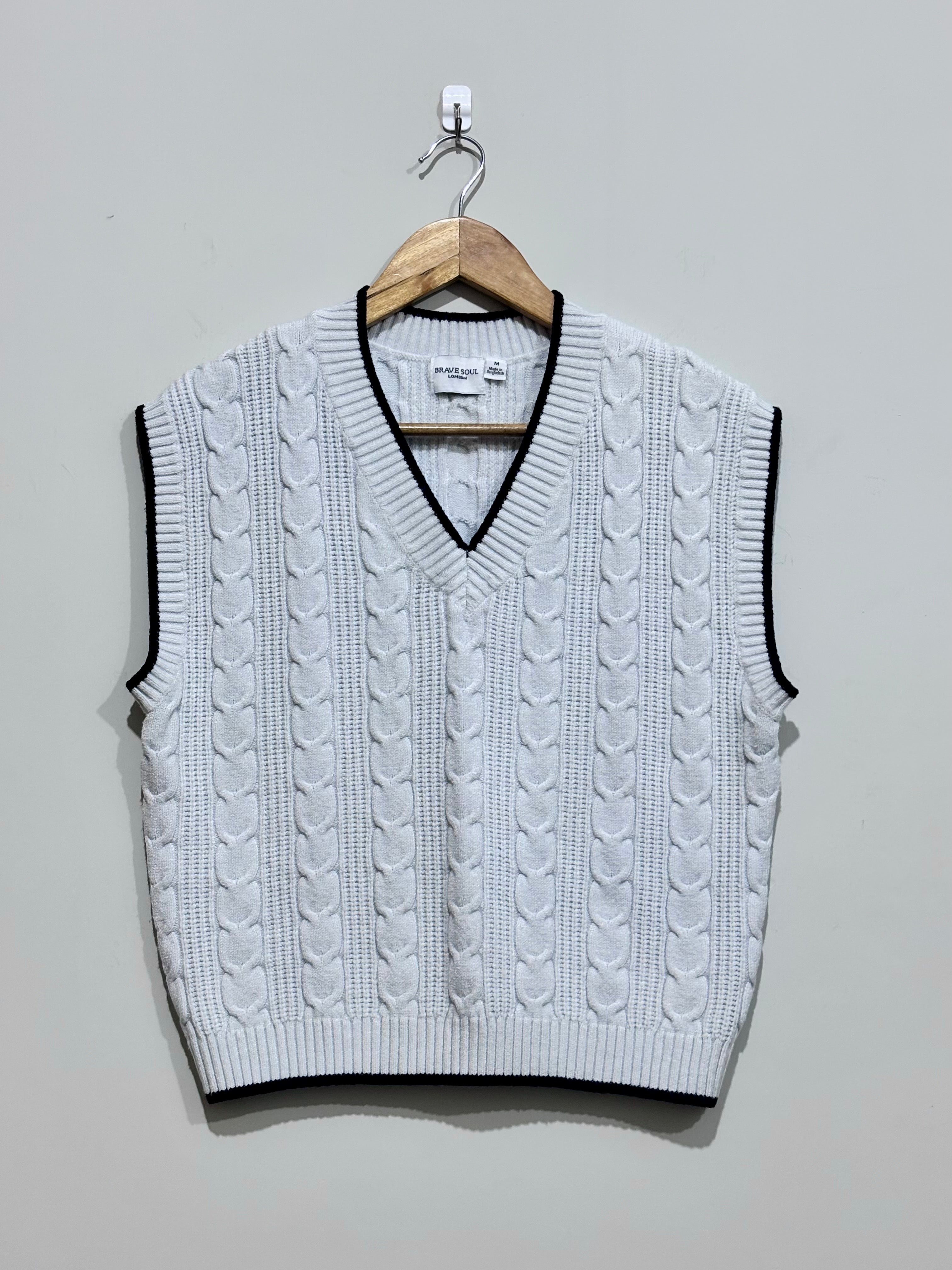 White cable-knit V-neck vest with black contrast trim