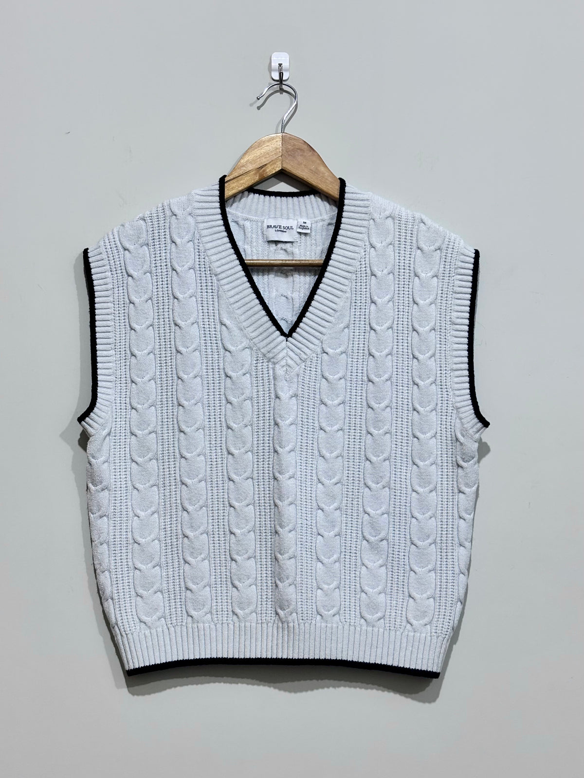 White cable-knit V-neck vest with black contrast trim