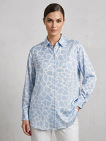 Woman wearing a light blue patterned shirt against a gray background