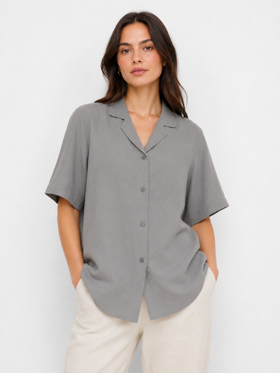 Woman wearing a gray short-sleeve blouse against a white background