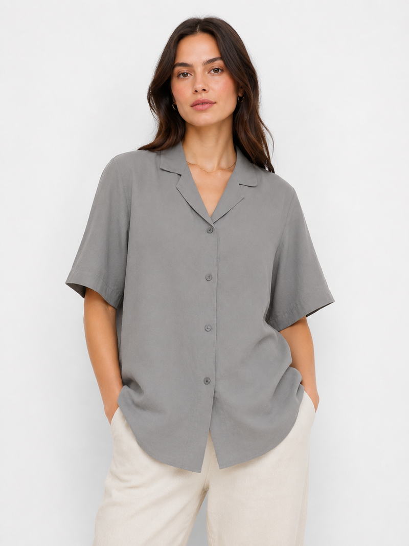 Woman wearing a gray short-sleeve blouse against a white background