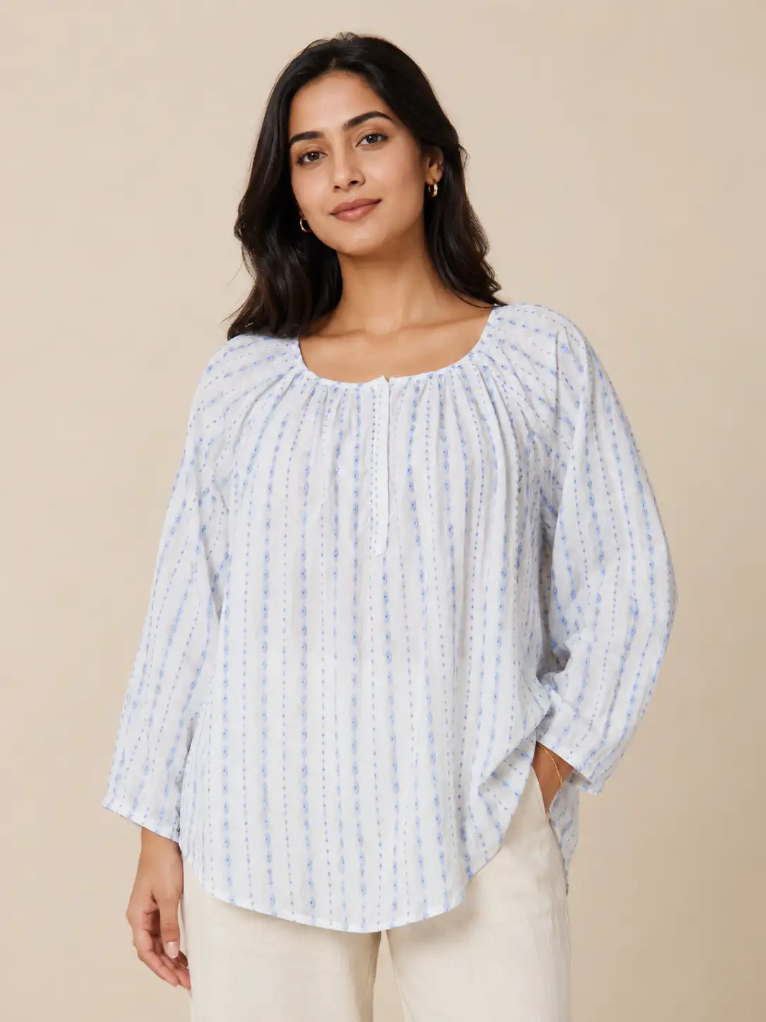 Woman wearing a light blue striped blouse against a beige background