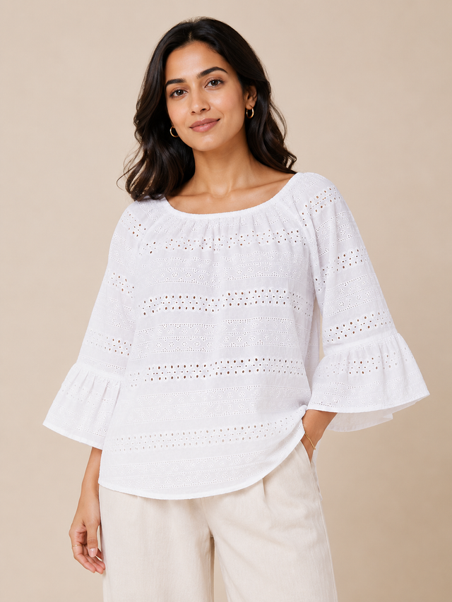 Woman wearing a white blouse with ruffled sleeves against a beige background