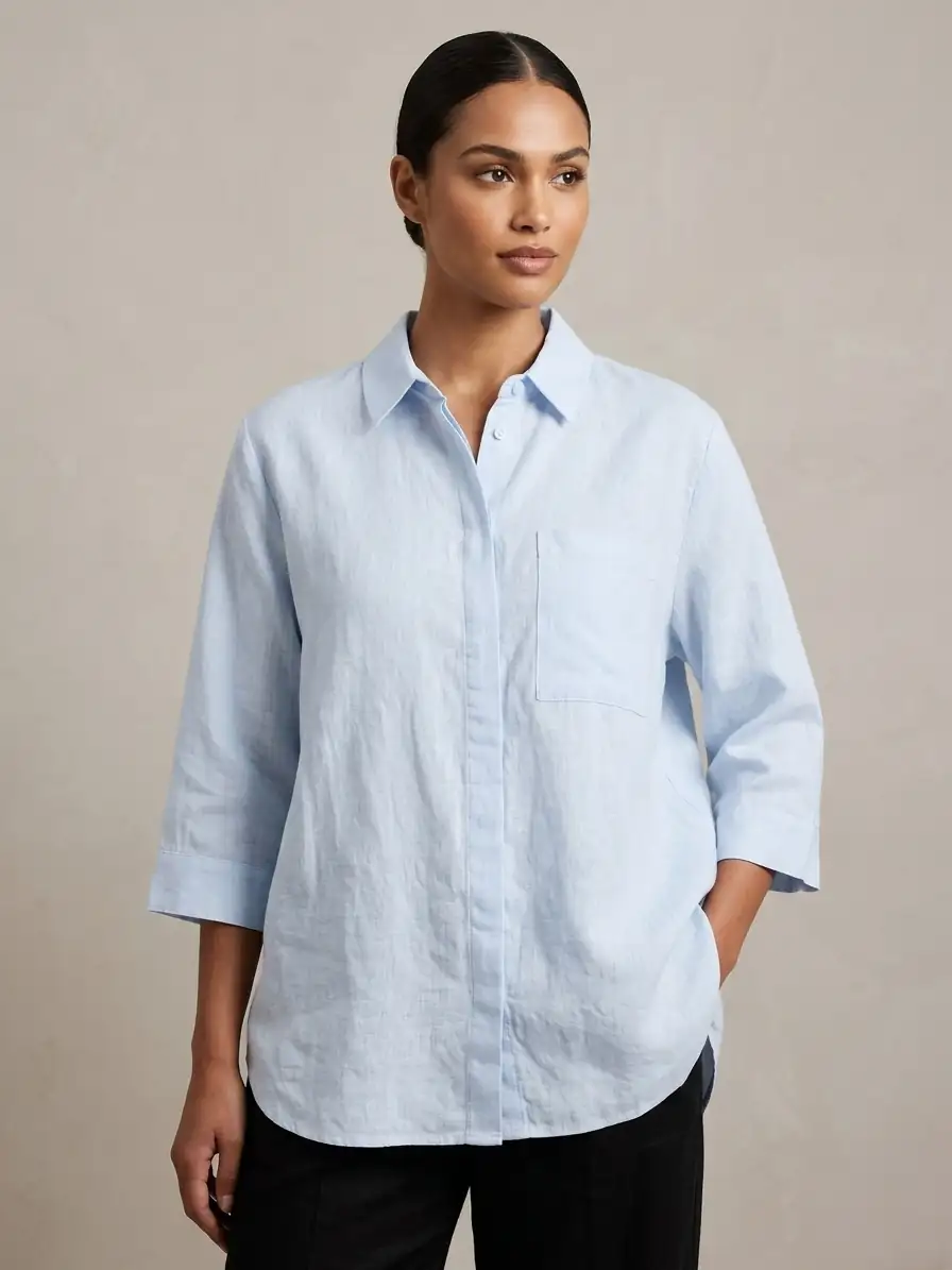Woman wearing a light blue button-up shirt against a beige background