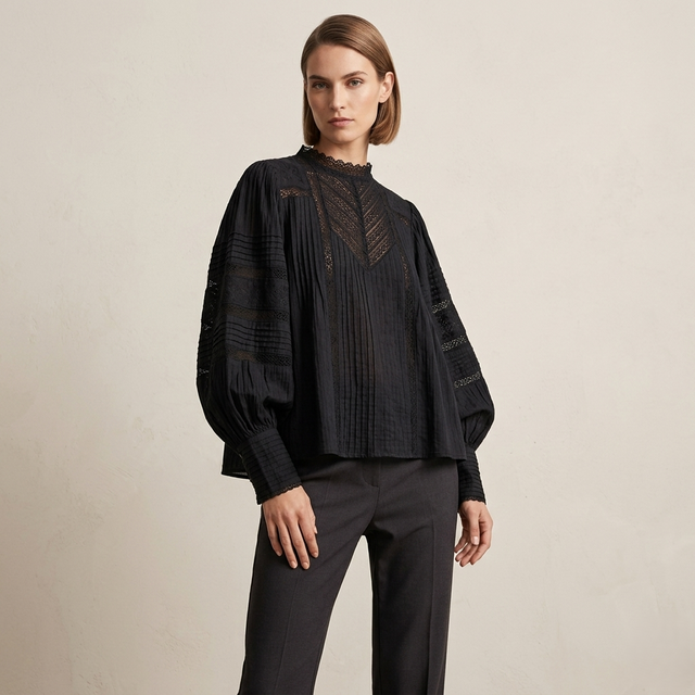Woman wearing a black textured top and pants on a beige background