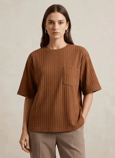 Woman wearing a brown ribbed t-shirt with a pocket on a beige background