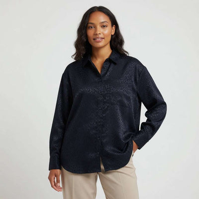 Woman wearing a dark blue patterned shirt against a plain background