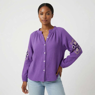 Woman wearing a purple embroidered blouse against a white background