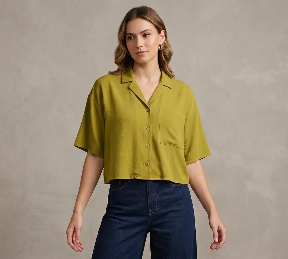 Woman wearing a green shirt and blue jeans against a neutral background