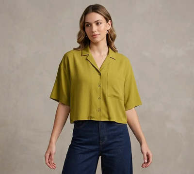 Woman wearing a green shirt and blue jeans against a neutral background