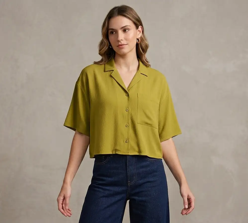Woman wearing a green shirt and blue jeans against a neutral background