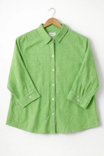 Green striped shirt on a hanger against a white background