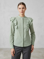 Woman wearing a green blouse with ruffled details against a plain background
