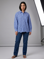 Woman wearing a blue lace blouse and jeans against a gray background