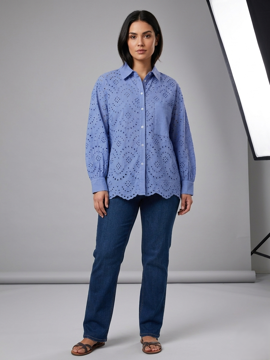 Woman wearing a blue lace blouse and jeans against a gray background