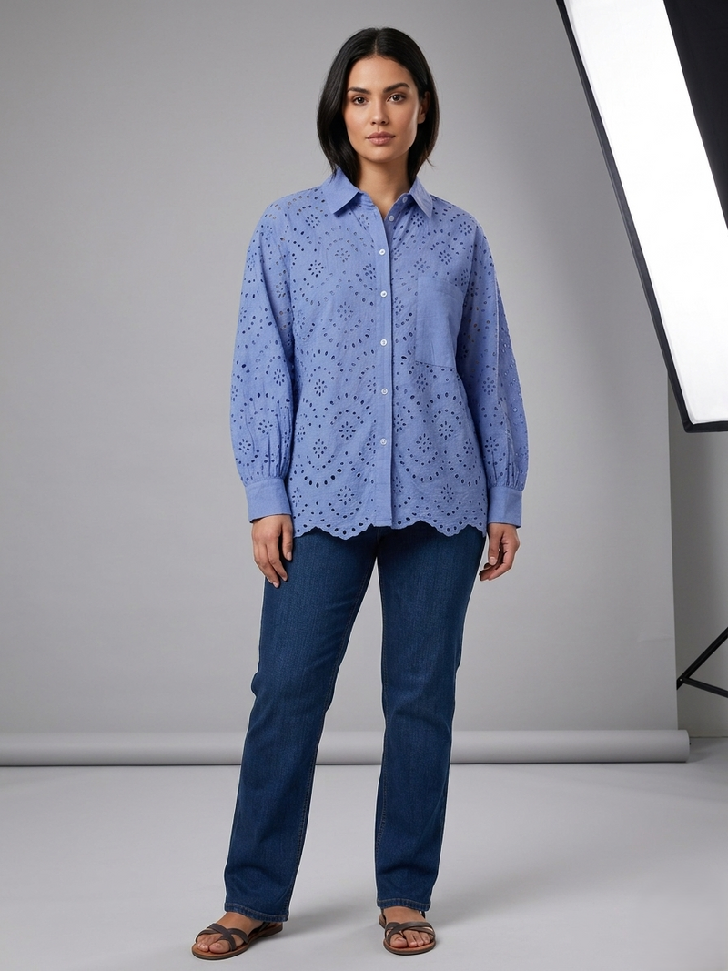 Woman wearing a blue lace blouse and jeans against a gray background