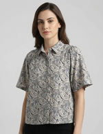 Woman wearing a patterned shirt against a plain background