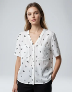 Woman wearing a white blouse with black pattern on a gray background